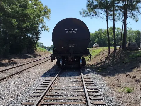 Vagão-tanque parado na linha de trem, entre pinheiros